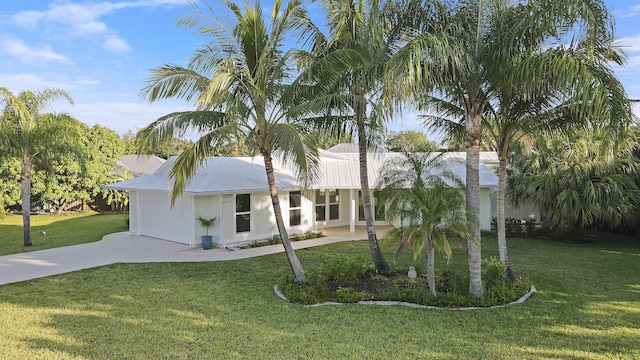 single story home with metal roof, a front yard, and driveway
