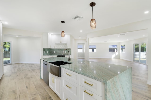 kitchen featuring tasteful backsplash, visible vents, an island with sink, a sink, and stainless steel dishwasher