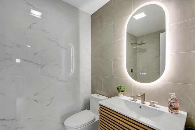 bathroom with tile walls, vanity, a shower, and toilet