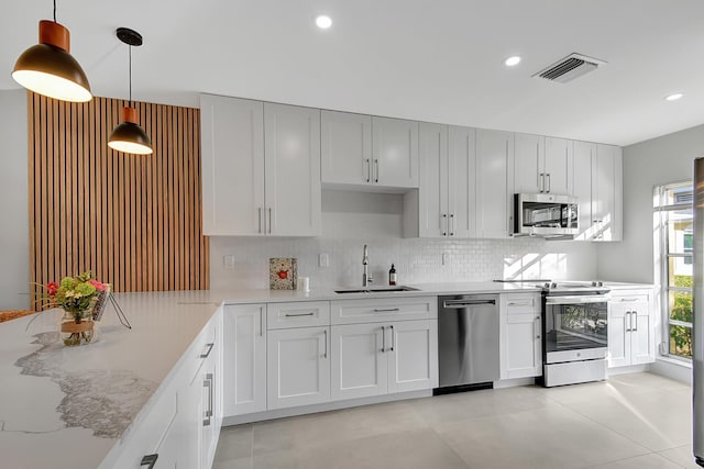 kitchen with visible vents, appliances with stainless steel finishes, hanging light fixtures, a sink, and backsplash