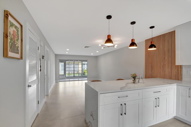 kitchen featuring hanging light fixtures, light stone countertops, and white cabinets