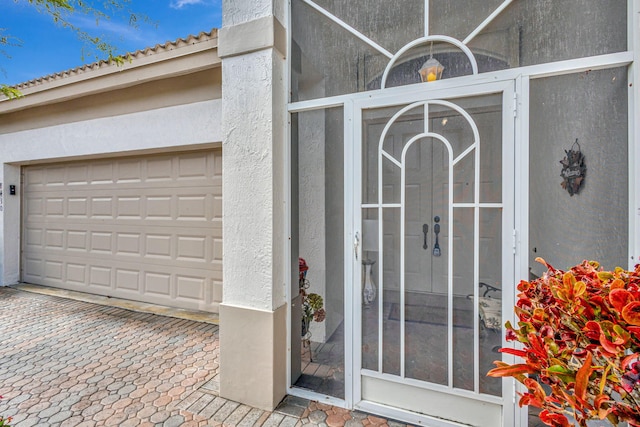 8430 Marsala Way, Boynton Beach, FL 33472 - view of exterior entry featuring a garage, stucco siding, a tiled roof, and driveway