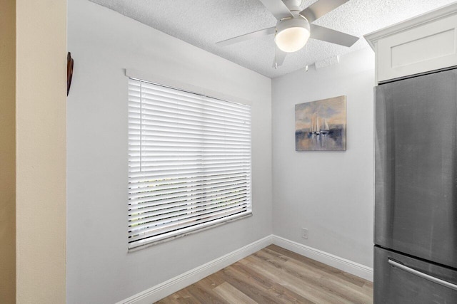 unfurnished dining area with ceiling fan, light hardwood / wood-style floors, and a textured ceiling