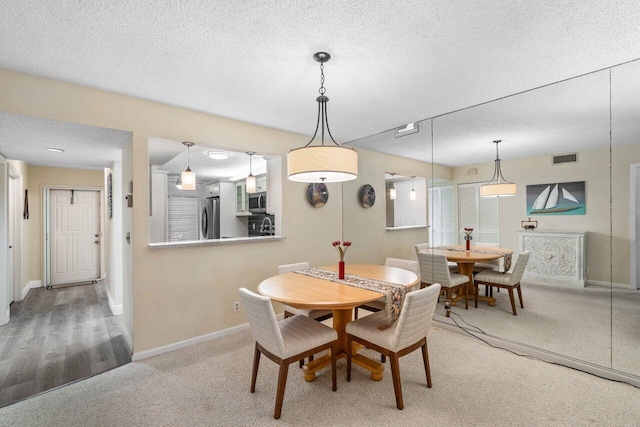 carpeted dining area with a textured ceiling