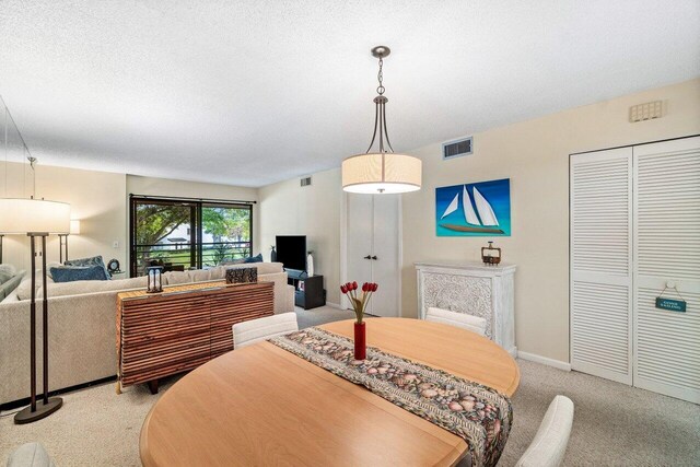 dining area with light colored carpet and a textured ceiling