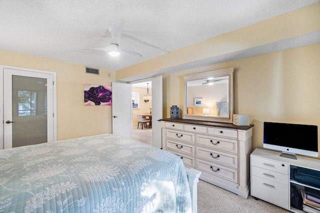 carpeted bedroom featuring ceiling fan and a textured ceiling