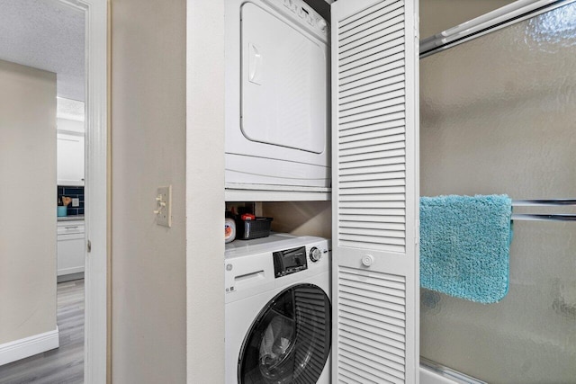 clothes washing area featuring stacked washing maching and dryer and hardwood / wood-style floors