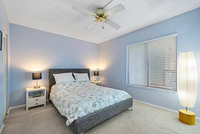 bedroom featuring ceiling fan, light colored carpet, and a textured ceiling