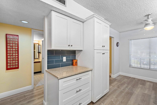 kitchen with white cabinetry, backsplash, ceiling fan, a textured ceiling, and light hardwood / wood-style flooring