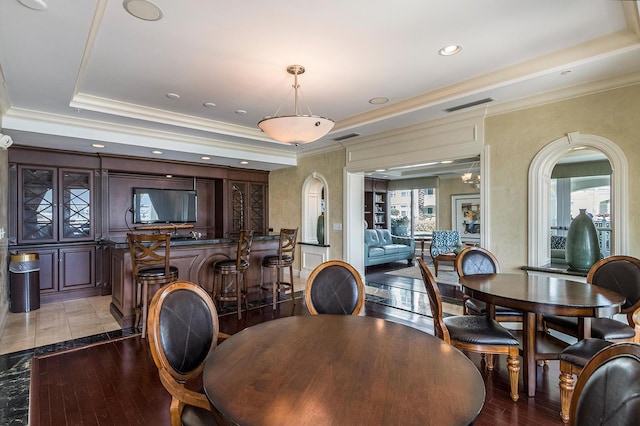 dining space with a tray ceiling, ornamental molding, and light hardwood / wood-style floors