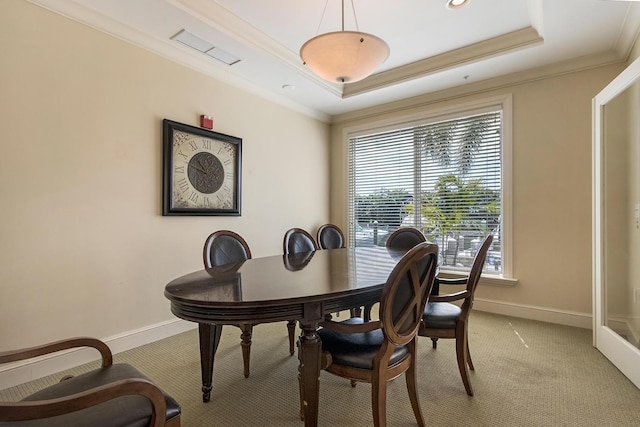 carpeted dining area with crown molding and a tray ceiling