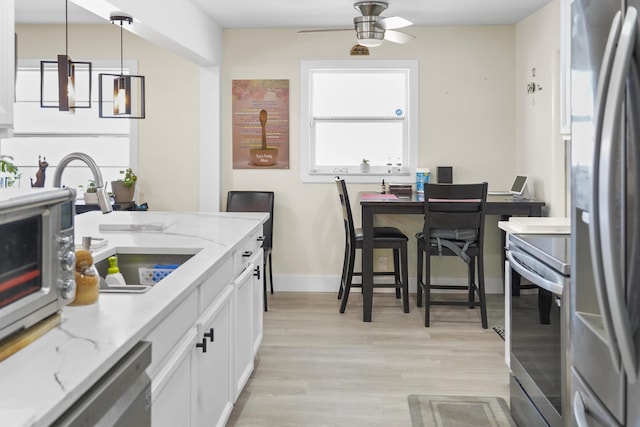 kitchen featuring stainless steel appliances, decorative light fixtures, light stone countertops, and white cabinets