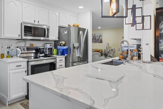 kitchen with white cabinetry, appliances with stainless steel finishes, light stone countertops, and hanging light fixtures