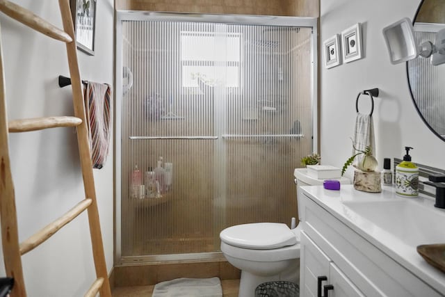 bathroom featuring a shower with door, vanity, tile patterned floors, and toilet