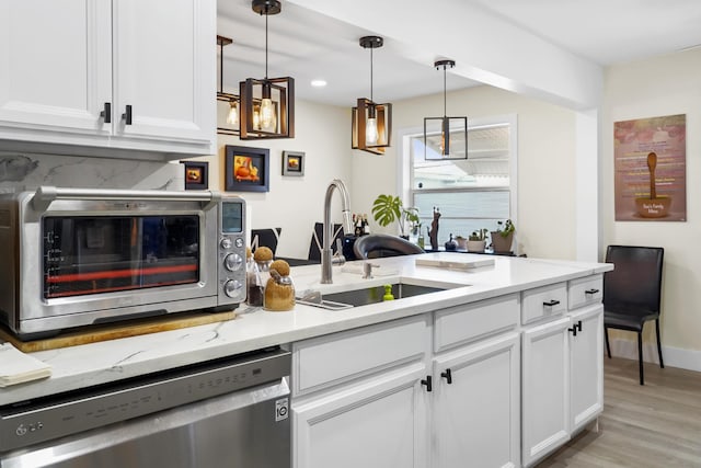 kitchen with sink, hanging light fixtures, light hardwood / wood-style floors, white cabinets, and stainless steel dishwasher