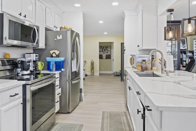 kitchen with sink, light stone counters, decorative light fixtures, appliances with stainless steel finishes, and white cabinets