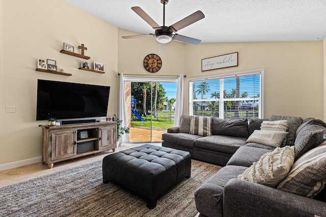 living room featuring vaulted ceiling, ceiling fan, and a textured ceiling