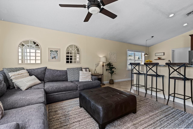 living room featuring ceiling fan, lofted ceiling, and a textured ceiling