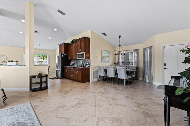 kitchen with appliances with stainless steel finishes, lofted ceiling, backsplash, and decorative light fixtures