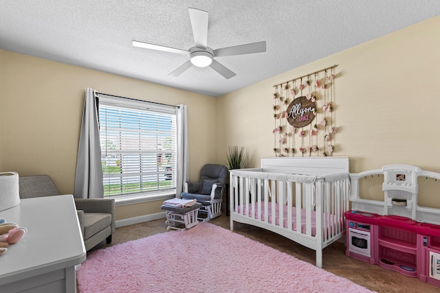 bedroom featuring a crib, a textured ceiling, and ceiling fan