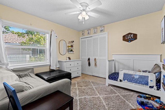 bedroom featuring light carpet, a textured ceiling, a closet, and ceiling fan