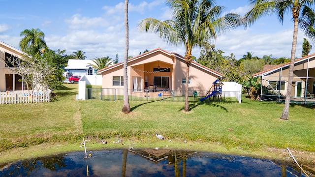 back of house with a water view and a lawn