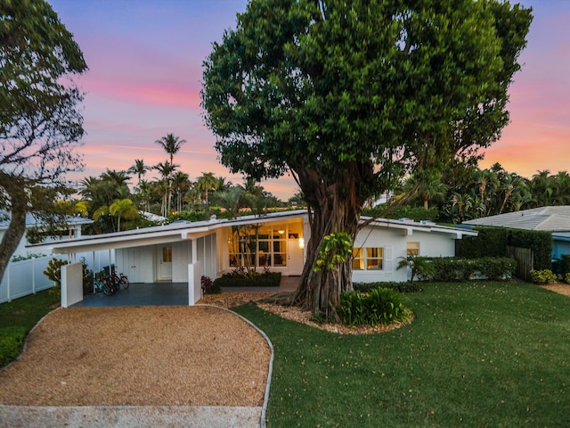 ranch-style home featuring a carport and a yard