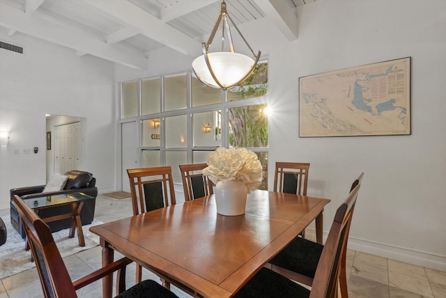 dining room with beam ceiling and a towering ceiling