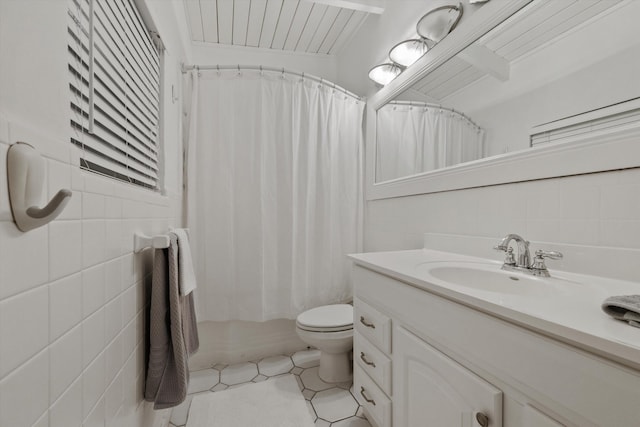 bathroom with vanity, toilet, tile patterned flooring, and tile walls