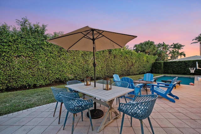 patio terrace at dusk with a fenced in pool