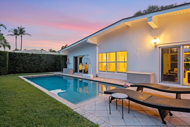 pool at dusk with a yard and a patio area