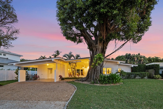 ranch-style home with a carport and a lawn