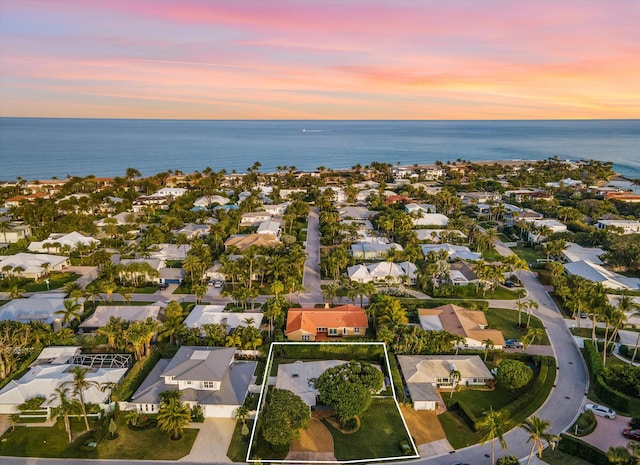 aerial view at dusk featuring a water view