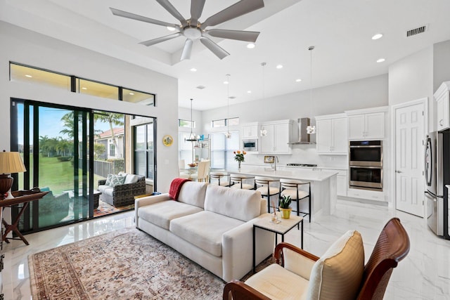 living room with a high ceiling and ceiling fan with notable chandelier