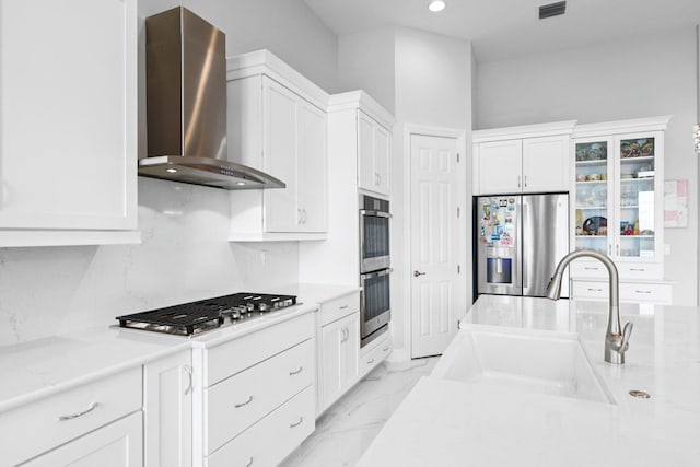 kitchen featuring stainless steel appliances, white cabinetry, sink, and wall chimney exhaust hood