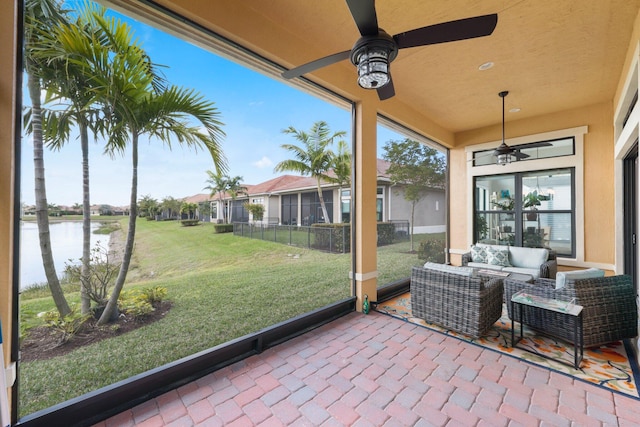 sunroom / solarium with a water view, ceiling fan, and plenty of natural light