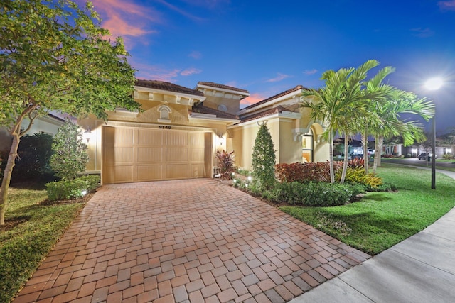 mediterranean / spanish-style home featuring a garage and a lawn