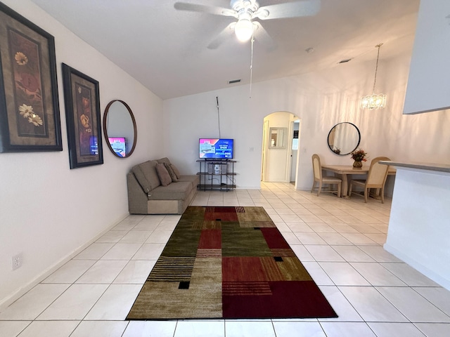 tiled living room with lofted ceiling and ceiling fan with notable chandelier