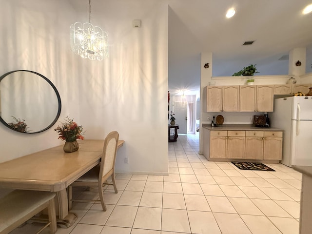 kitchen featuring light tile patterned flooring, pendant lighting, light brown cabinetry, white refrigerator, and a notable chandelier