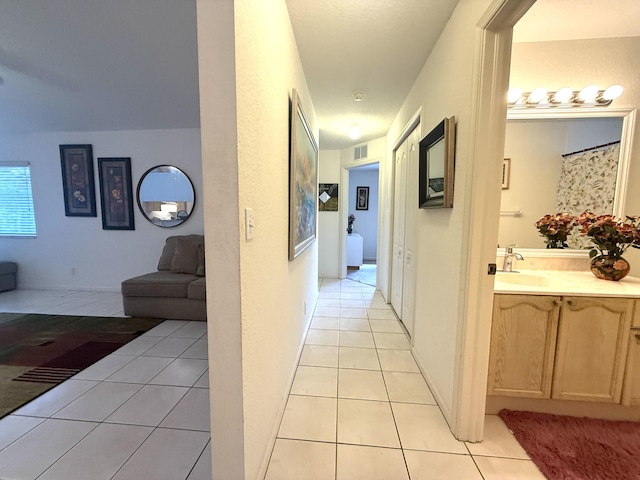 corridor featuring sink and light tile patterned floors