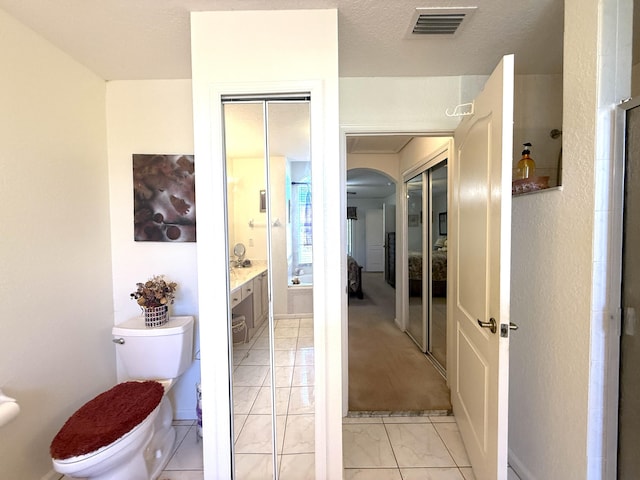 bathroom featuring vanity, a textured ceiling, tile patterned floors, and toilet