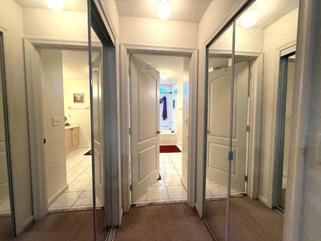 hall with light tile patterned floors and a textured ceiling