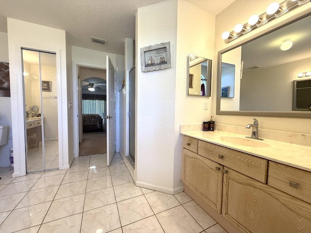 bathroom with vanity, ceiling fan, a textured ceiling, and walk in shower