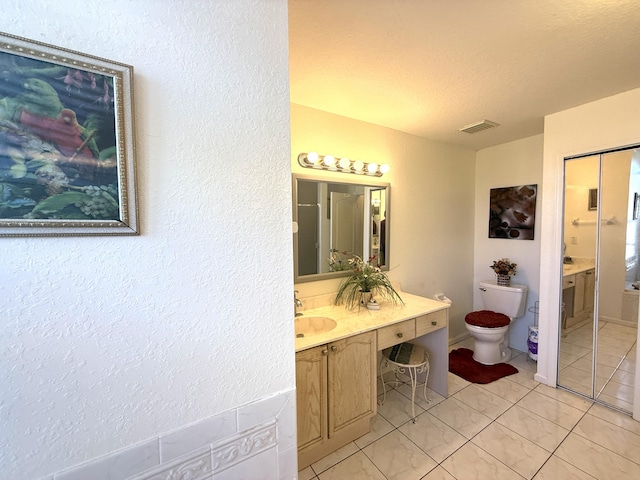 bathroom with tile patterned flooring, vanity, a textured ceiling, and toilet