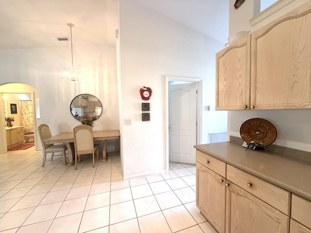 kitchen featuring an inviting chandelier, high vaulted ceiling, light tile patterned floors, light brown cabinets, and pendant lighting