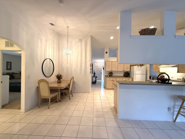 kitchen featuring light tile patterned flooring, light brown cabinetry, decorative light fixtures, white fridge, and an inviting chandelier