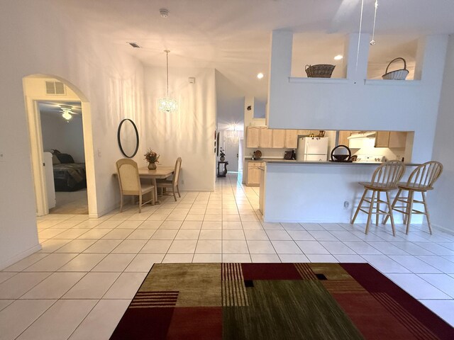 kitchen with white refrigerator, light brown cabinets, kitchen peninsula, and light tile patterned floors