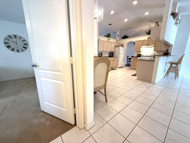 kitchen with light tile patterned flooring, a kitchen bar, decorative light fixtures, light brown cabinets, and white refrigerator