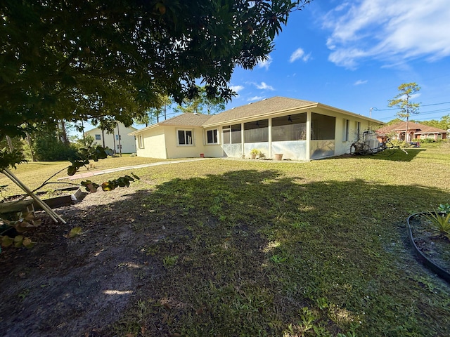 back of house featuring a lawn and a sunroom