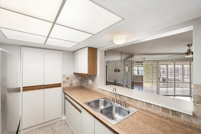 kitchen with sink, white cabinets, decorative backsplash, light tile patterned floors, and ceiling fan